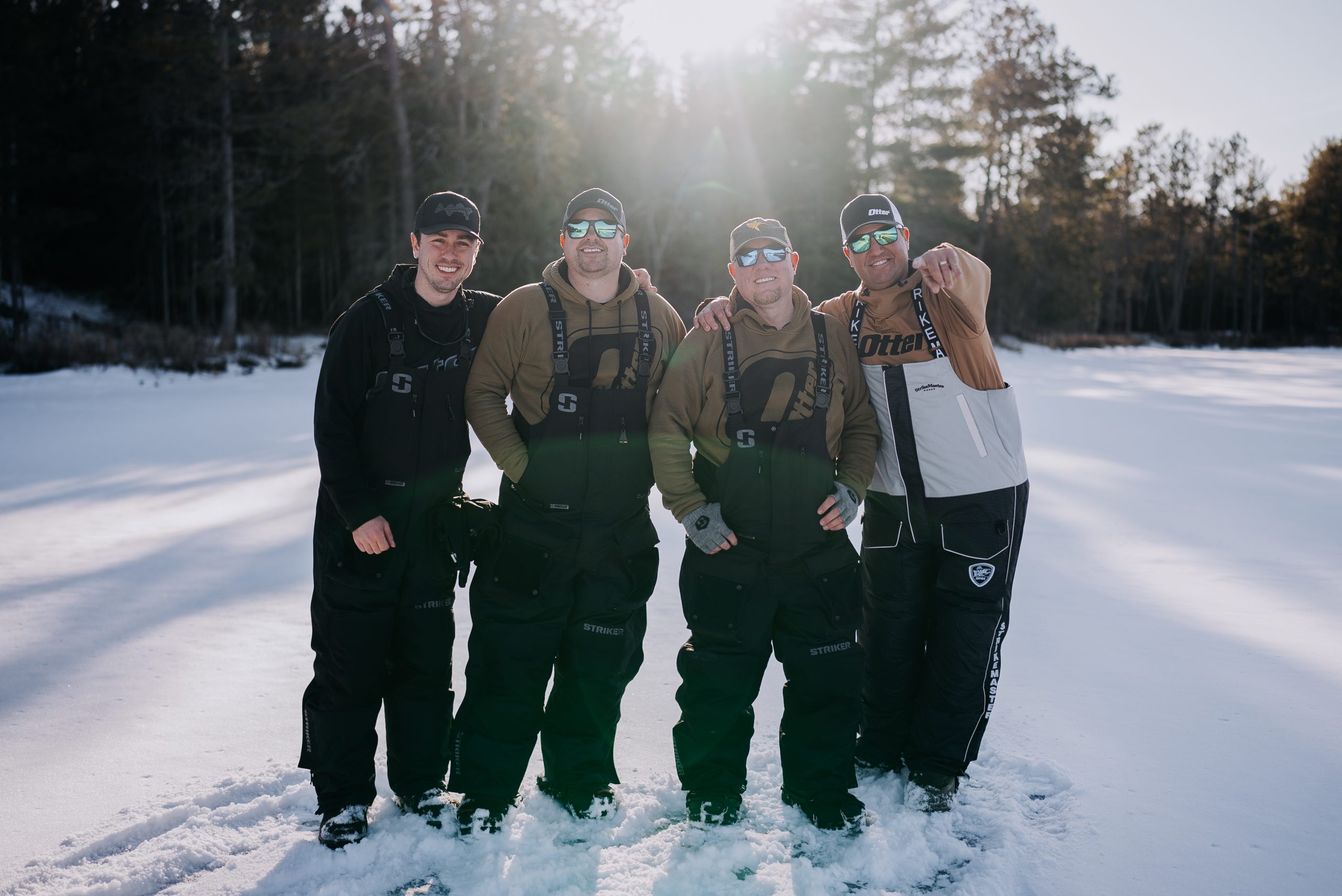 Four smiling men look at the camera on a frozen lake